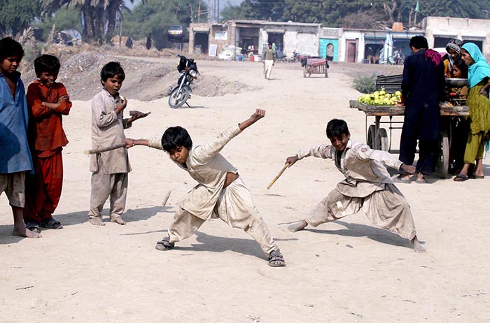 Gypsy children playing traditional game (Gilli danda) at Tando Yousuf.