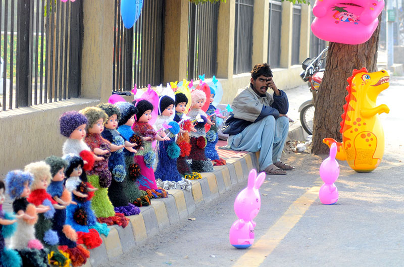 A vendor waiting for customers to sell beautiful dolls at his roadside setup