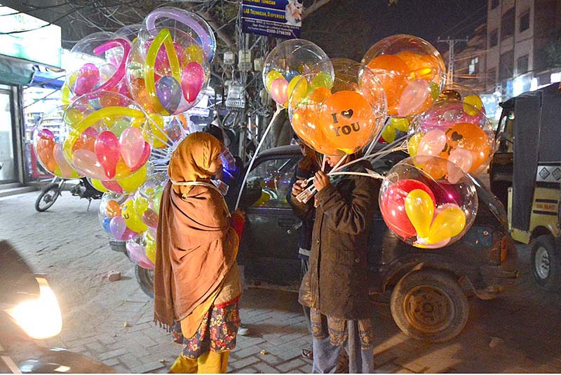 Young street vendor displaying the lighting balloons to attract the customers at Latifabad