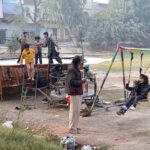 Children enjoying on swings and trampoline in a local park
