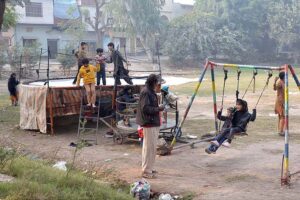 Children enjoying on swings and trampoline in a local park