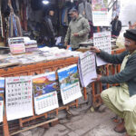 A vendor displaying New Year 2024 calendars in Anarkali Bazaar.