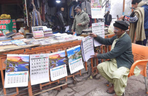 A vendor displaying New Year 2024 calendars in Anarkali Bazaar.