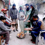 People sitting around fire to keep themselves warm in cold weather in the City.