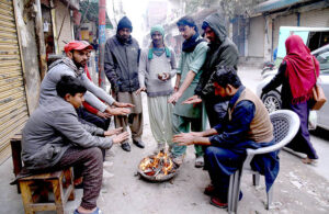 People sitting around fire to keep themselves warm in cold weather in the City.