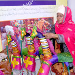 A woman is standing at her stall decorating the kughu litter at Gaddafi Stadium