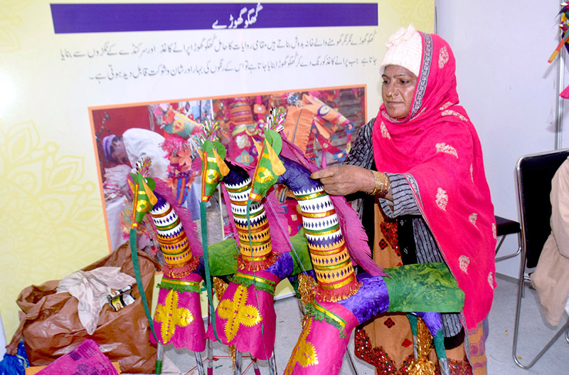 A woman is standing at her stall decorating the kughu litter at Gaddafi Stadium