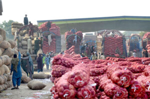 A large number of laborers are busy unloading onions on the delivery truck at the vegetable Market