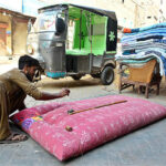 A worker busy in stitching quilt for customers at his workplace