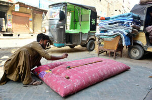 A worker busy in stitching quilt for customers at his workplace