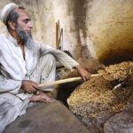 A labourer roasting peanuts in a traditional way at his workplace in Fridous Market
