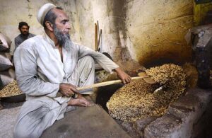 A labourer roasting peanuts in a traditional way at his workplace in Fridous Market