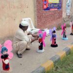 A vendor arranging and displaying toys on footpath to attract the customers.