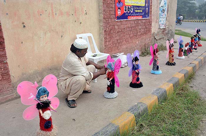 A vendor arranging and displaying toys on footpath to attract the customers.