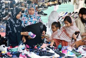 Women selecting and purchasing second hand shoes from vendor at Station road
