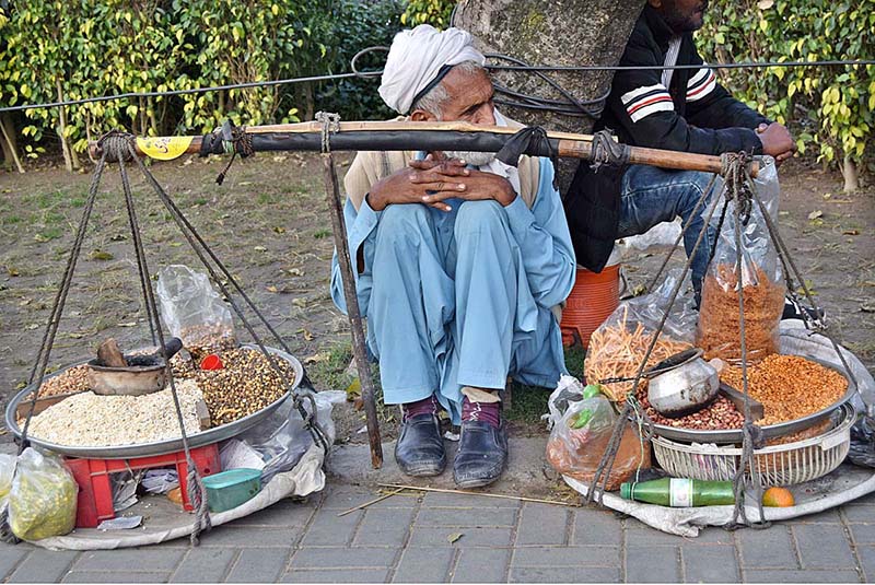 An elderly man waiting for costumers sitting on the roadside