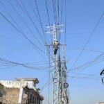 A WAPDA worker busy installing new electric cables on a pylon at Tramri area.