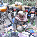 An aged woman displays household items to sell for livelihood outside H-9 weekly bazar in federal capital