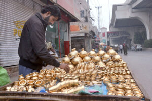 Vendor is busy displaying golden color Golak and other items to attract customers on his handcart