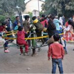 Children enjoy swings in a local park at Bagh Jinnah