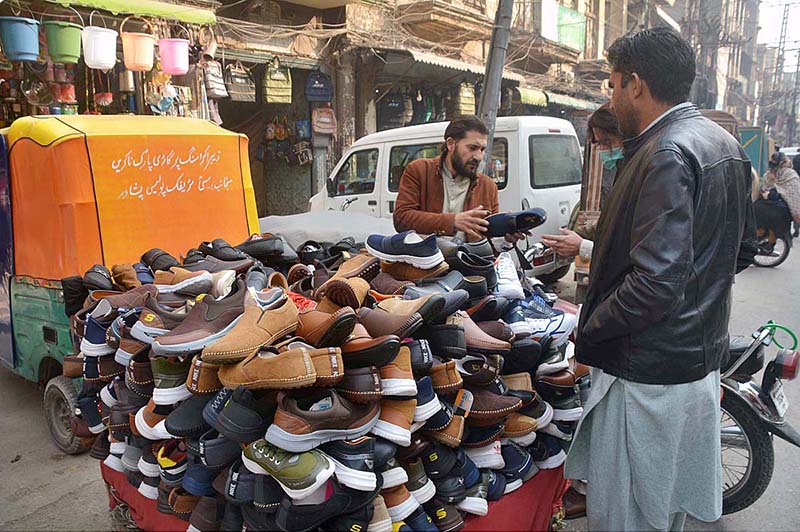 Customers selecting and purchasing shoes from roadside vendor at Qissa Khawani Bazar