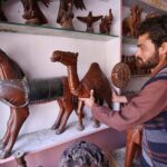 Vendor selling and displaying handmade wooden decoration items at his shop.