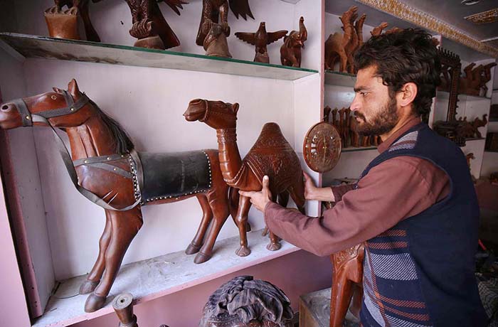 Vendor selling and displaying handmade wooden decoration items at his shop.