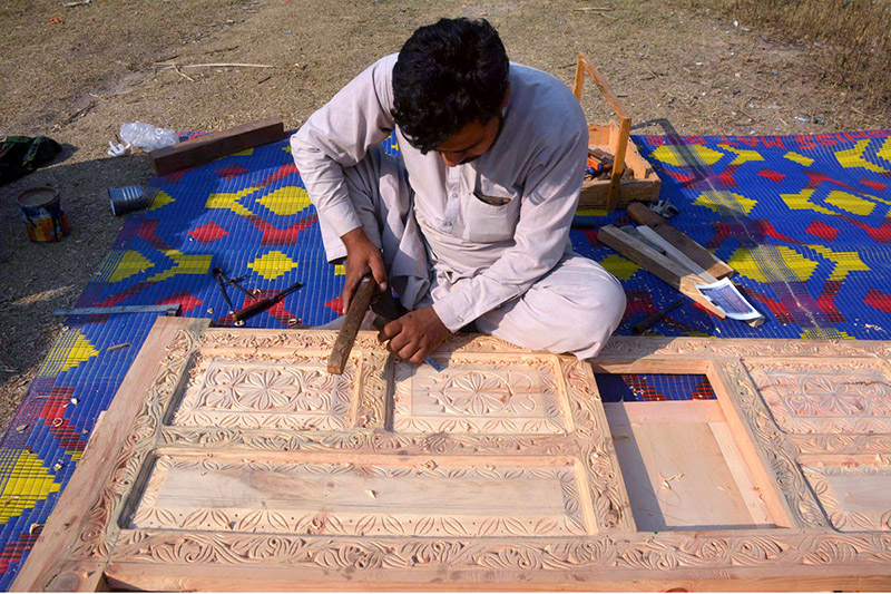 Laborer busy in designing on a wooden door at his workplace in Charsadda road.