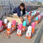A vendor displaying and selling thermos on footpath to attract customers outside Qasim Bagh