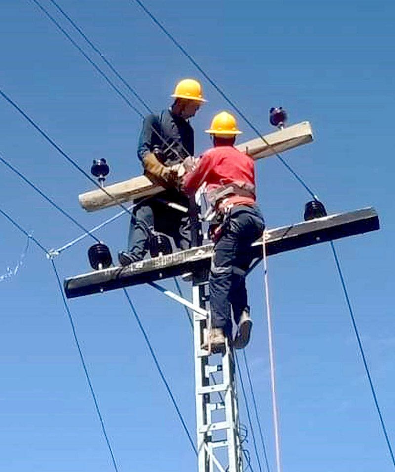 Water and Power department staffers busy in installing new electricity poll on the road side.