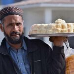 A vendor displaying sweet and salty items to attract customers while shuttling on the road.