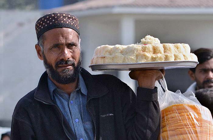 A vendor displaying sweet and salty items to attract customers while shuttling on the road.