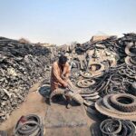 Laborer busy in cutting scrap tyres at godown near Ring road