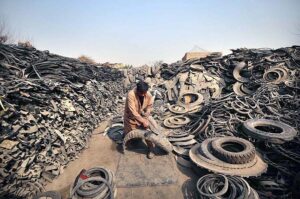 Laborer busy in cutting scrap tyres at godown near Ring road