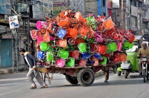 Labourer pulling handcart loaded with children bicycles to be delivered at Iqbal Road