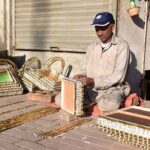 Skilled worker busy making gift baskets at his roadside setup.