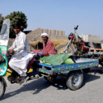 A loader rickshaw driver towing an out of order loader rickshaw to a mechanic for repair at Ratodero Road