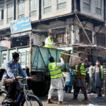Municipal Corporation staff are picking up the illegal encroachments in Jhang Bazar and loading them into the vehicle.