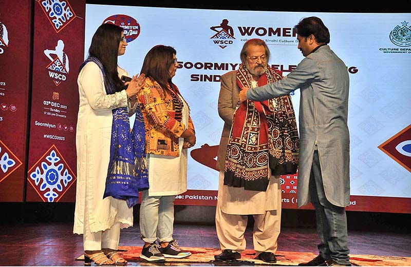 Group photo of Federal Minister Madad Ali Sindhi receiving a Sindhi Ajrak from the organizer during the Sindhi Cultural Day event organized by Soormiyun at PNCA