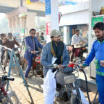 Motorcycle riders standing in queue to get petrol at PSO fuel station after decrease in petrol prices