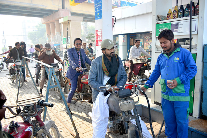 Motorcycle riders standing in queue to get petrol at PSO fuel station after decrease in petrol prices