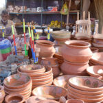 Vendor displaying traditional hookah and other clay-made items at roadside setup
