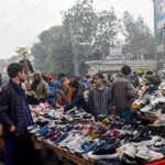 Customers selecting and purchasing second hand shoes from the roadside vendors