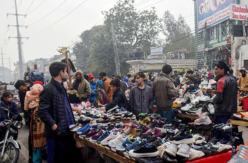 Customers selecting and purchasing second hand shoes from the roadside vendors