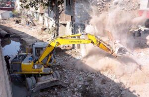 Municipal Corporation staff are picking up the illegal encroachments in Jhang Bazar and loading them into the vehicle.
