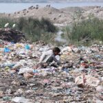 A gypsy youngster searching and collecting recycle items from heap of garbage at site area