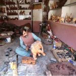 An artisan busy making wooden decoration items at his workplace near Tehsil area