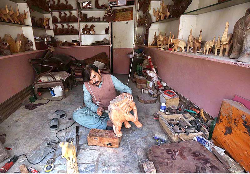 An artisan busy making wooden decoration items at his workplace near Tehsil area