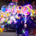 Young street vendors displaying the lighting balloons to attract the customers at Latifabad.