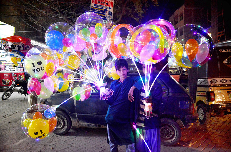 Young street vendors displaying the lighting balloons to attract the customers at Latifabad.